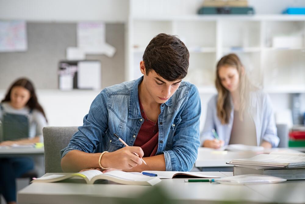 Jovem concentrado durante um teste de aptidão, refletindo sobre suas habilidades e possibilidades de carreira em um ambiente educacional.
