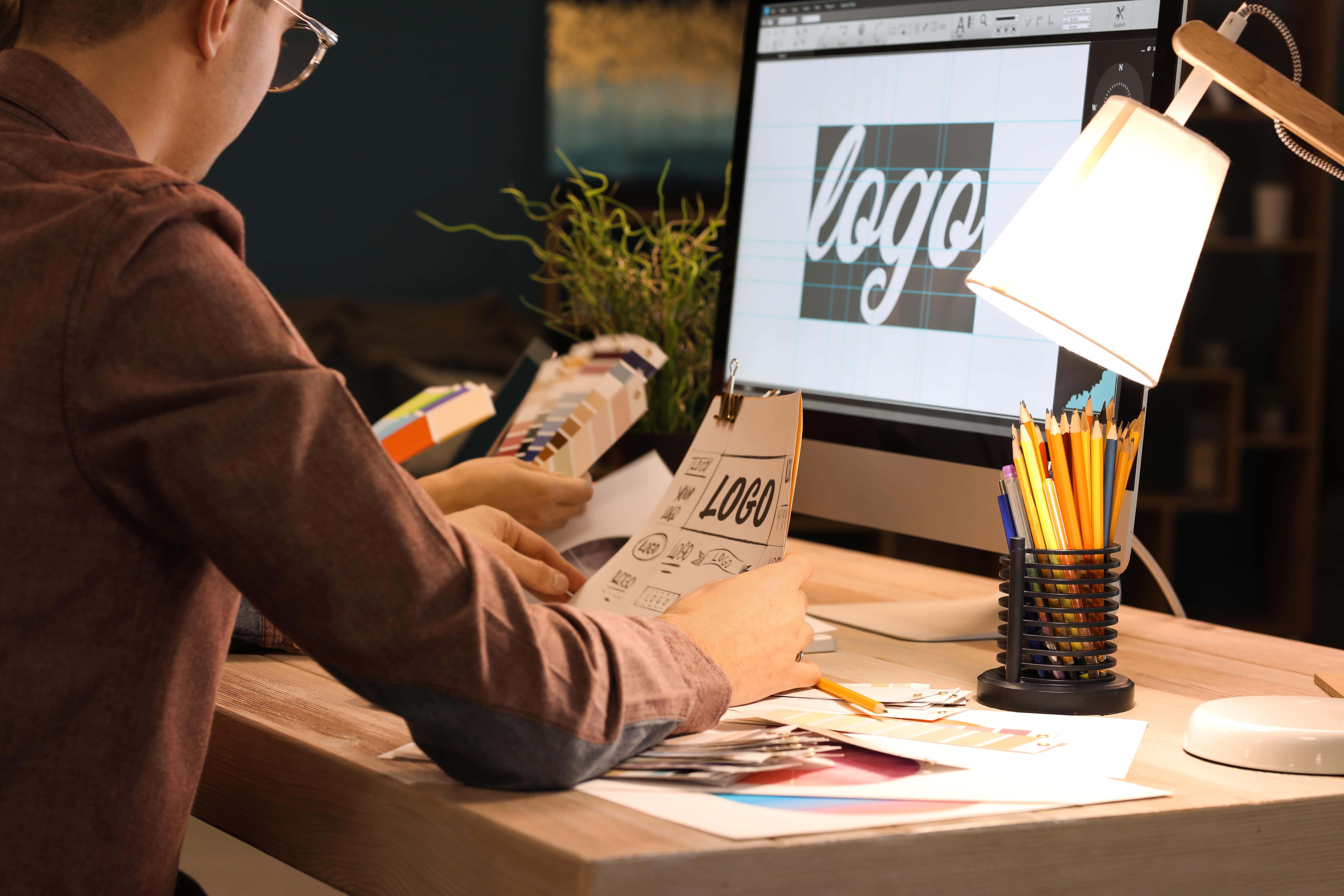 Jovem trabalhando na criação de identidade visual em computador, representando como o design gráfico é destaque nos cursos para ganhar dinheiro desde cedo